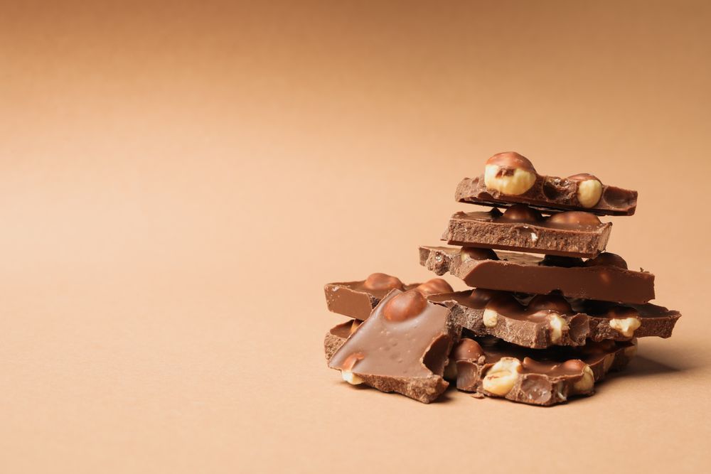 Chocolate pieces on beige background. Sweet food