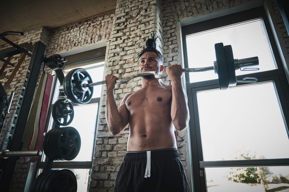 Black man exercising with barbell in gym