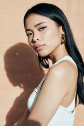 Portrait of woman with dark hair looking at camera from the side with shadow behind her
