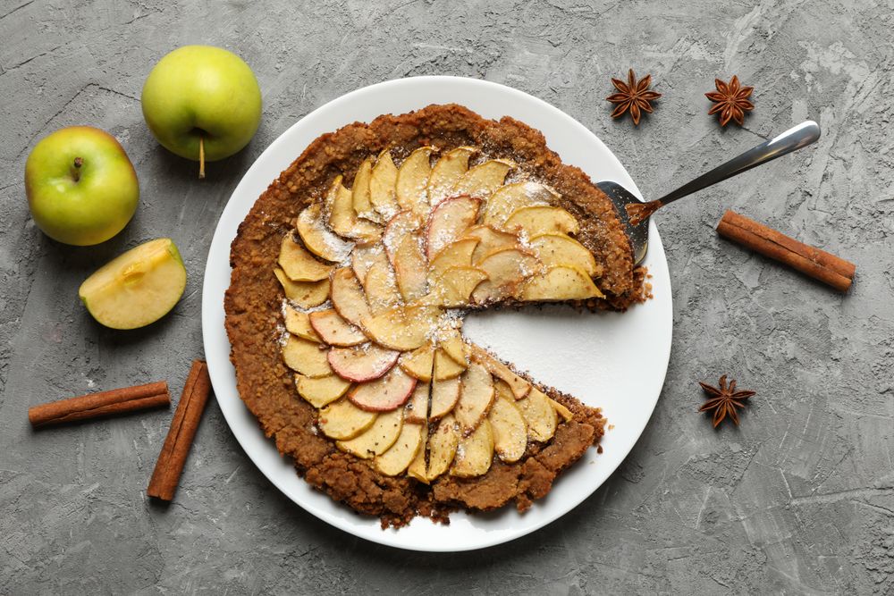 Composition with apple pie and ingredients on gray background, top view