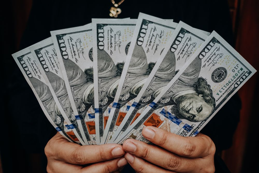 Person holding one hundred dollar bills