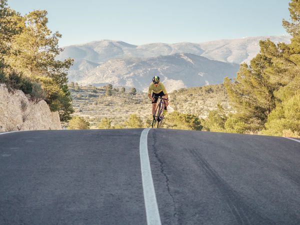 healthy man riding a bicycle on a mountain road in a sunny day