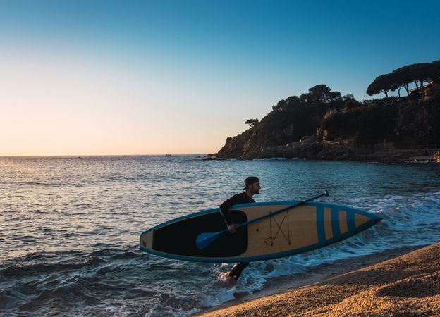 Man practicing paddle surfing with neoprene in a sunrise