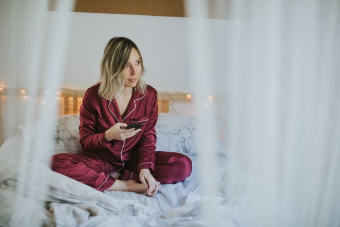 Woman sitting in bed with smartphone