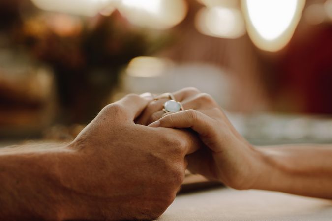 Cropped shot of couple holding hands sitting at table