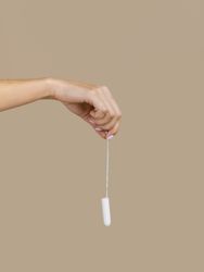 Hand holding tampon front view