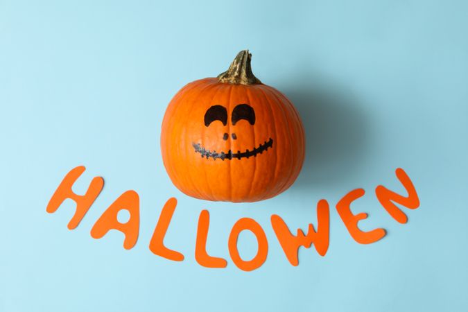 Pumpkin with smile and text Halloween on blue background