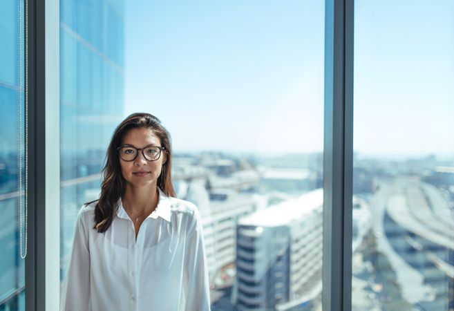 Business investor standing in office in high-rise building overlooking cityscape