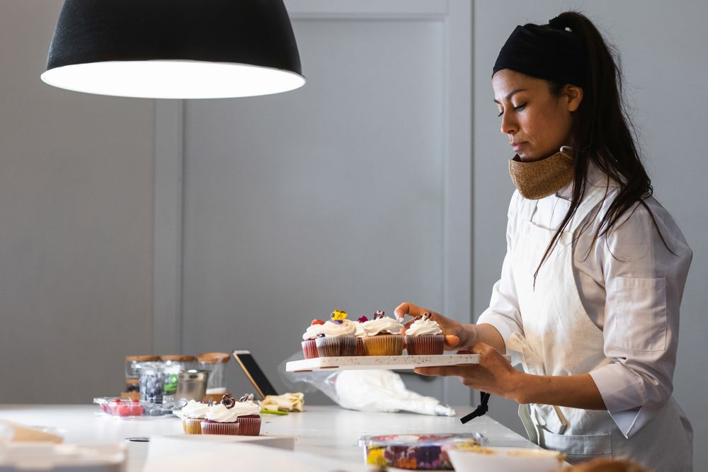 Female cook with cupcakes in kitchen