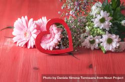 Decorative heart on pink flowers on rustic red table 0VMXYb