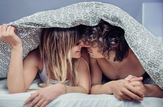 Smiling young couple in love smiling under duvet cover