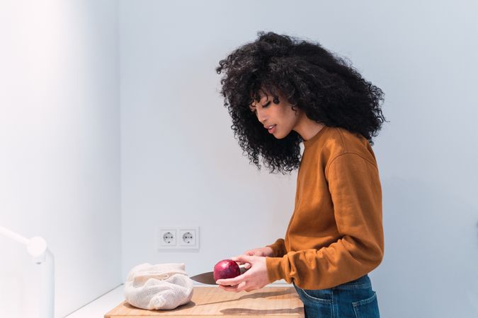 Black woman cutting apple in kitchen