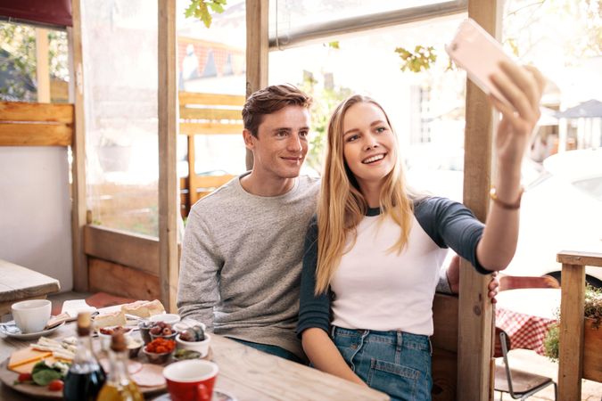 Young couple taking selfie with smart phone in school cafe