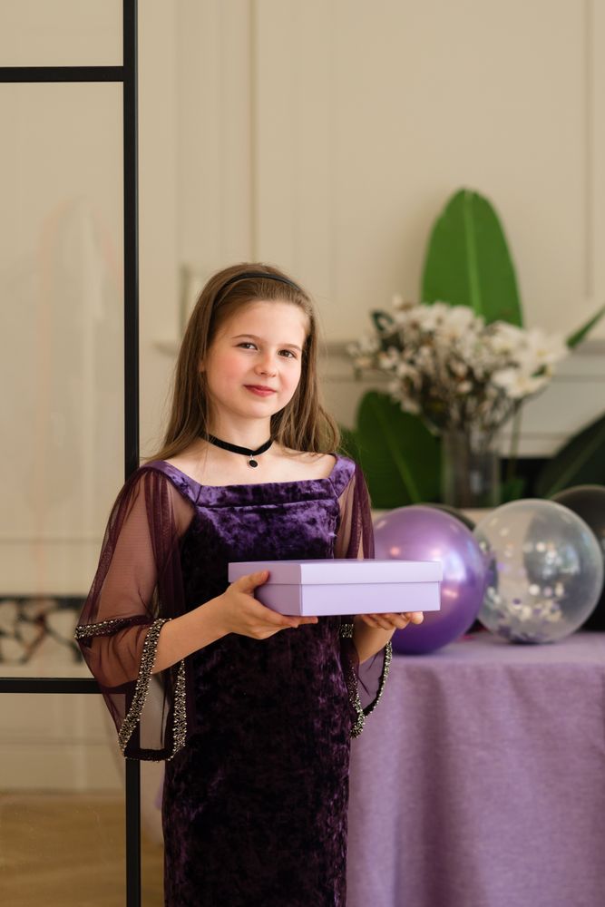 Girl holding gift box and smiling at birthday party.