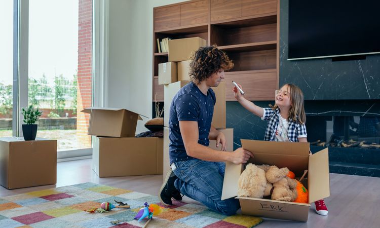 Child playing with father preparing moving boxes