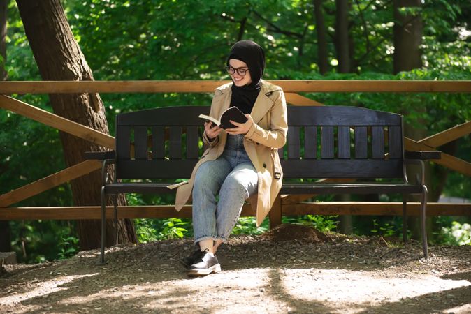 Middle Eastern woman engaged in a book while sitting on a park bench