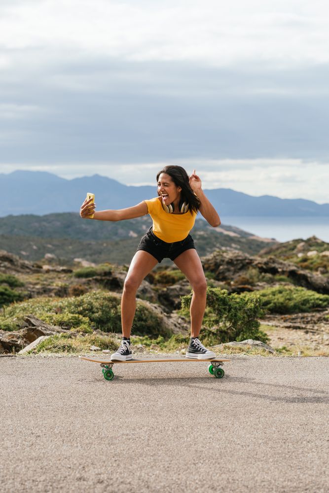 Smiling woman on longboard and taking selfie