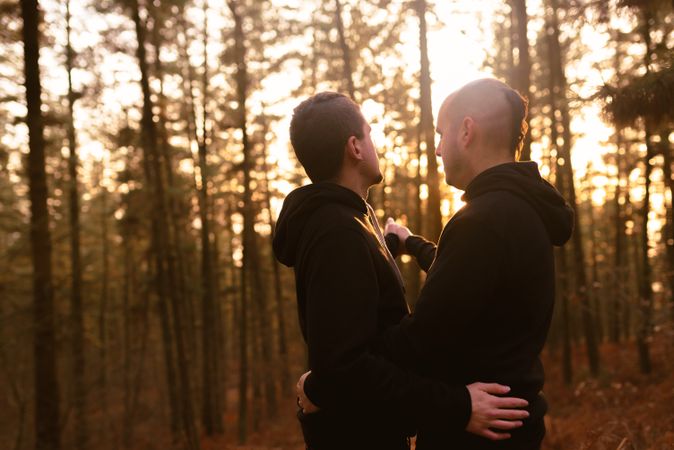 Men hugging in forest at sunset