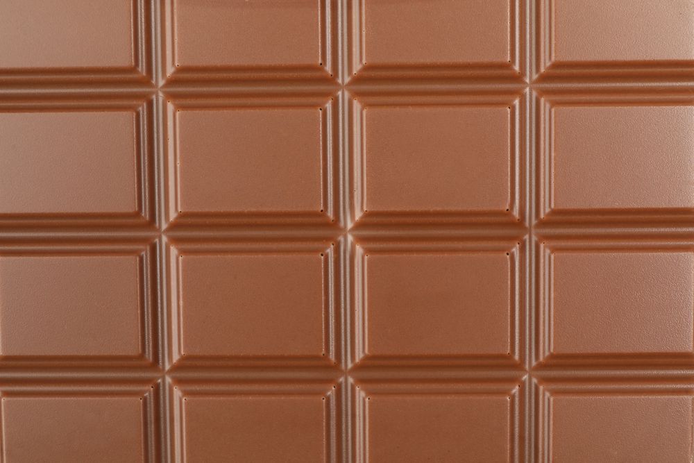 Different chocolate bars on whole background. Sweet food