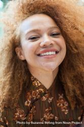 Close up portrait of a young woman with an afro smiling and looking into the camera bDjQQ5