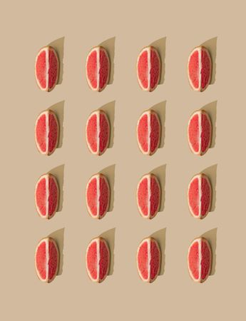 Pattern of grapefruit slices and pastel sand background