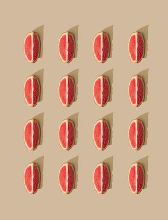 Pattern of grapefruit slices and pastel sand background