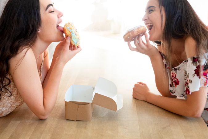 Happy women in sundresses with box of glazed desserts