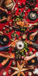 Group of people holding drinks at festive red table setting with cake, roast chicken, decorations
