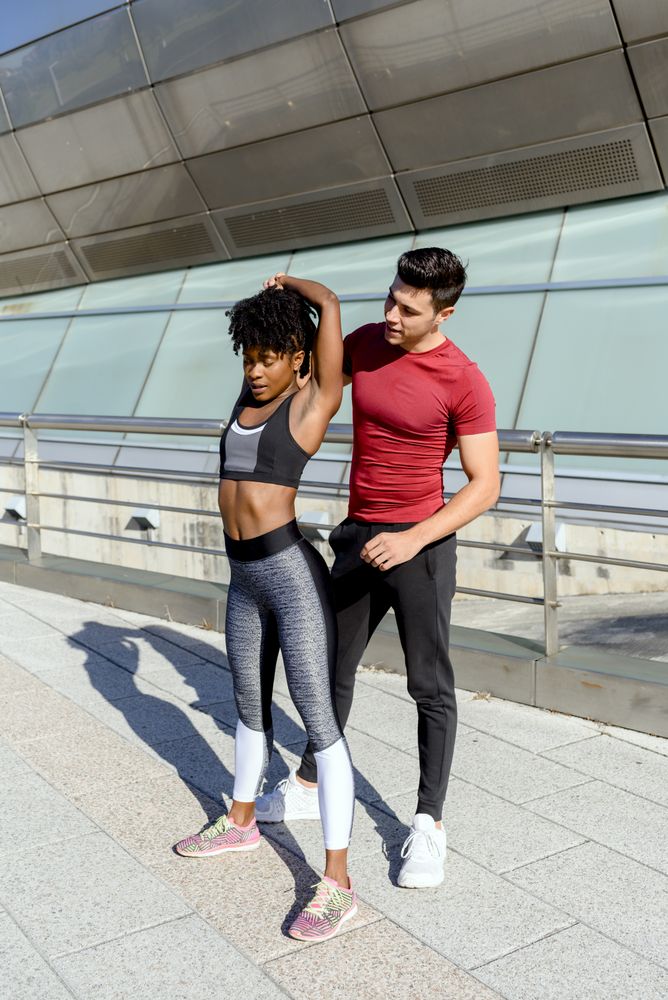 Male trainer helping woman in doing exercise