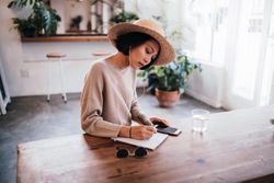 Young woman writing in a notebook at a coffee shop