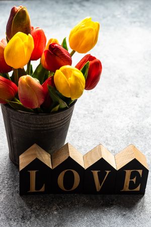 Valentine's day card concept with the word "love" and metal vase of tulips