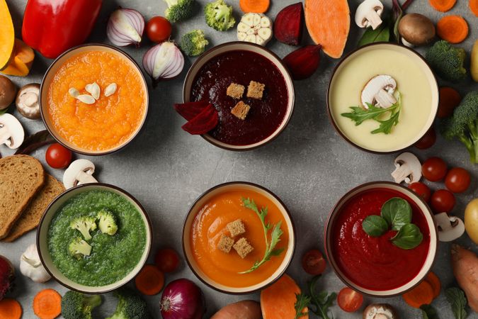Multi-colored soups in row with vegetables