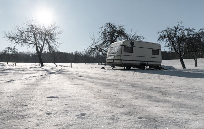 Snowy landscape at sunrise in an orchard with a camper van
