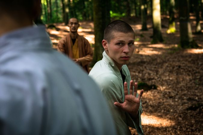 man training martial arts student in forest