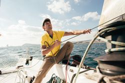 Man on yacht pulling the sail