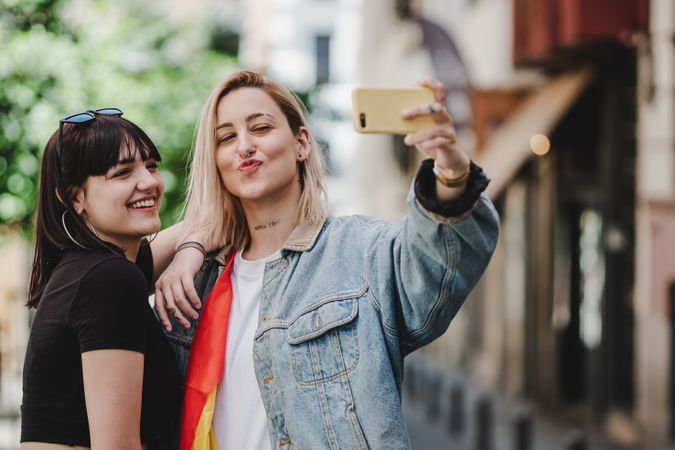 Happy lesbian couple taking selfie on street
