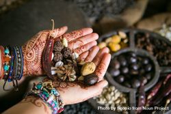 Person's hands with henna tattoo holding dried seeds 5p6avb
