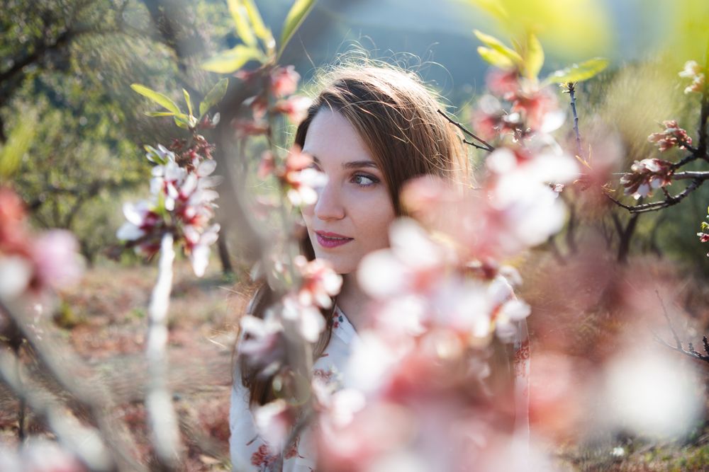 Young happy woman between trees in garden