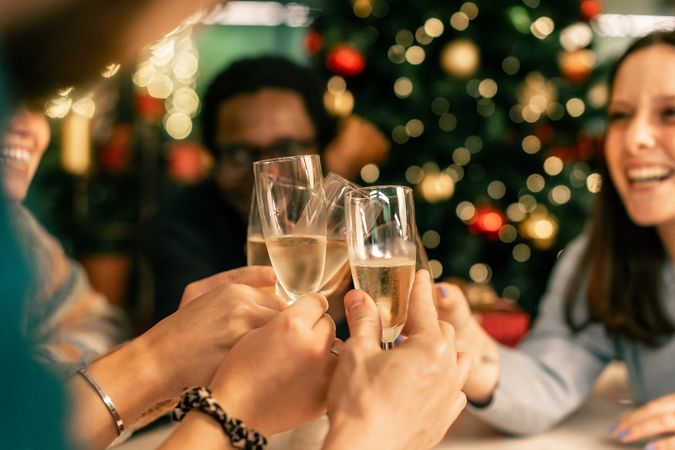 Diverse friends toasting with champagne, with a Christmas tree bokeh background.