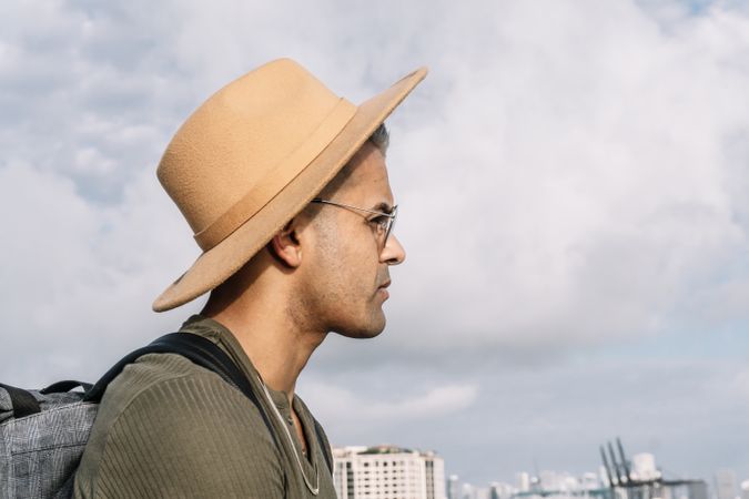 Side view of a man with a nice hat and glasses looking straight ahead.