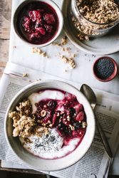 Delicious breakfast bowl with quinoa, rice and groats near tea cup and newspaper