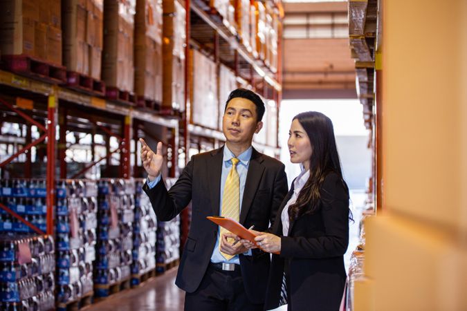 Two professional colleagues in warehouse going through inventory