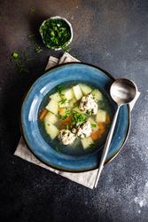 Bowl of healthy soup with potato and carrot and meat balls served on the table with copy space