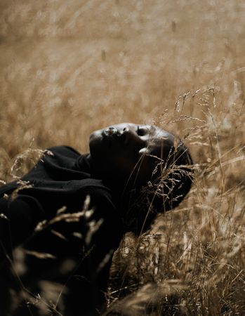 Woman in dark top lying on brown grass field