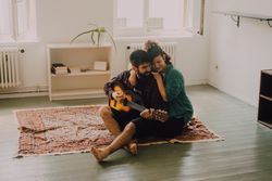Cheerful couple playing guitar at home
