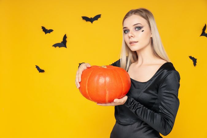 Concept of Halloween, young woman on yellow background