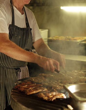 Man wearing apron standing at the grill