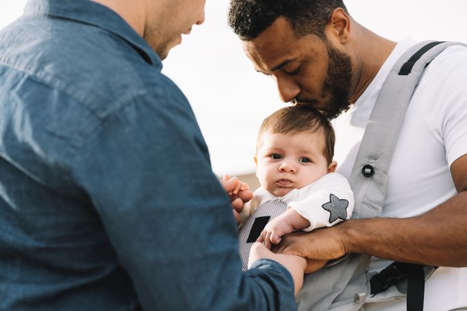 Unrecognizable diverse men walking with baby on nature