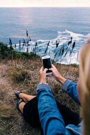 Person using smartphone while chilling at coast