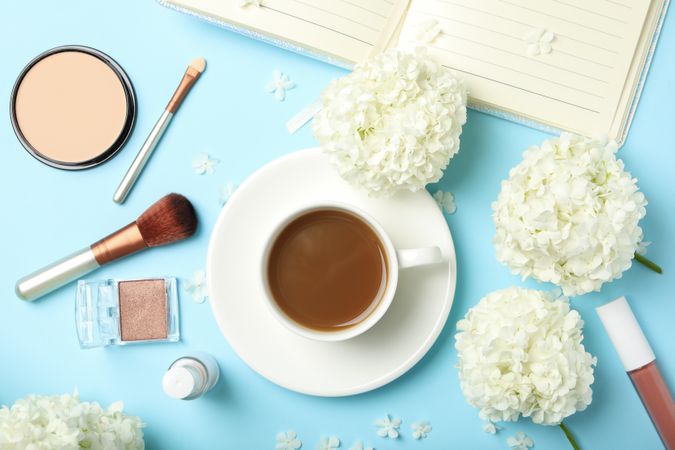 Composition with hydrangea flowers, coffee and cosmetics on blue background